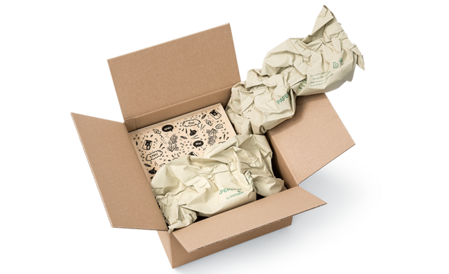 A cardboard box containing a wooden box and paper cushioning strips made from grass paper