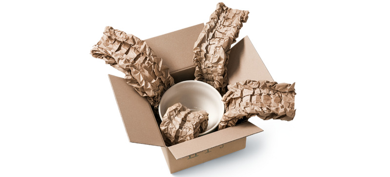 A cardboard box containing a bowl and brown paper cushioning