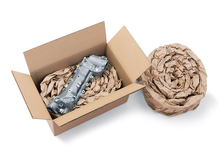 A cardboard box containing a component and paper cushioning made from rolled-up paper cushioning strips