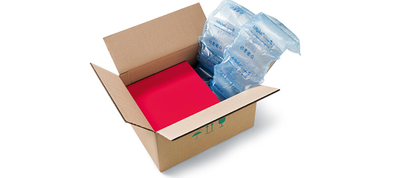 A cardboard box containing a red box and recycled air cushions