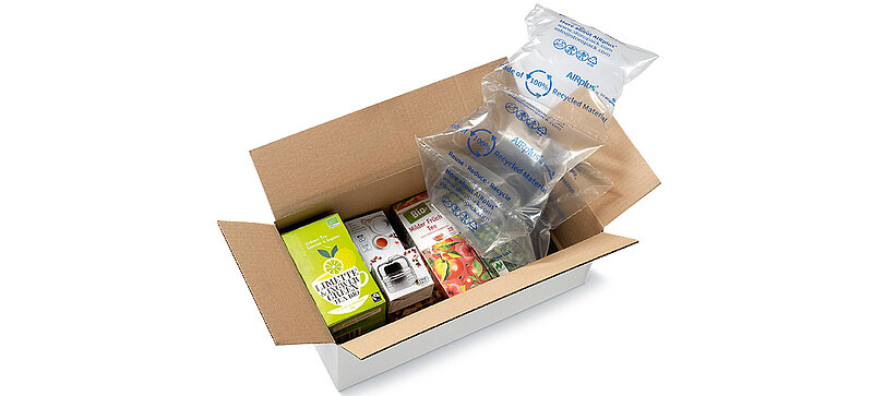 A cardboard box with packs of tea and 100% RECYCLED air cushions 