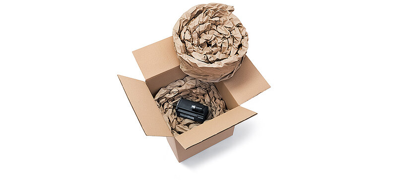 A cardboard box containing a component and paper cushioning made from rolled-up paper cushioning strips