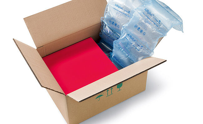 A cardboard box containing a red box and recycled air cushions